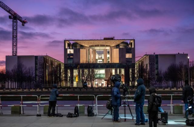 14 December 2025, Berlin: Media representatives stand outside the German Chancellery in the evening light as Ukrainian President Volodymyr Zelensky, his negotiating team and the US delegation meet inside to hold initial talks on the next steps toward a ceasefire in Ukraine. Photo: Michael Kappeler/dpa