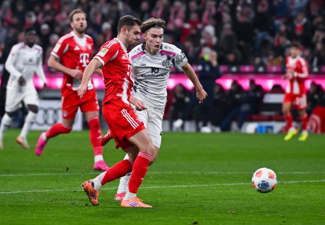 14 December 2025, Bavaria, Munich: Bayern Munich's Josip Stanisic (L) and Mainz's Kacper Potulski battle for the ball during the German Bundesliga soccer match between Bayern Munich and FSV Mainz 05 at the Allianz Arena. Photo: Sven Hoppe/dpa - WICHTIGER HINWEIS: Gemäß den Vorgaben der DFL Deutsche Fußball Liga bzw. des DFB Deutscher Fußball-Bund ist es untersagt, in dem Stadion und/oder vom Spiel angefertigte Fotoaufnahmen in Form von Sequenzbildern und/oder videoähnlichen Fotostrecken zu verwerten bzw. verwerten zu lassen.