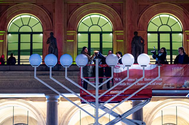 14 December 2025, Lower Saxony, Hanover: The Jewish community lights the menorah on Opera Square to mark the start of Hanukkah, the eight-day festival of lights commemorating the rededication of the Temple in Jerusalem in 165 BC. Photo: Moritz Frankenberg/dpa