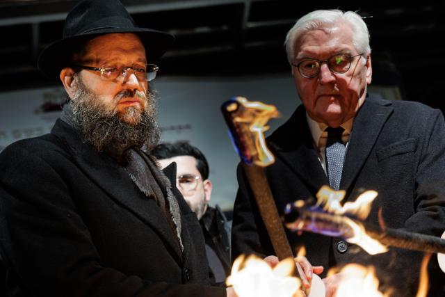 14 December 2025, Berlin: Rabbi Yehuda Teichtal (L) and German President Frank-Walter Steinmeier light the first candle of the Hanukkah menorah on Pariser Platz in front of the Brandenburg Gate to mark the start of the Jewish festival of lights. Following the deadly attack on a Hanukkah celebration of the Chabad community at Bondi Beach in Sydney, they called for prayer. Photo: Carsten Koall/dpa