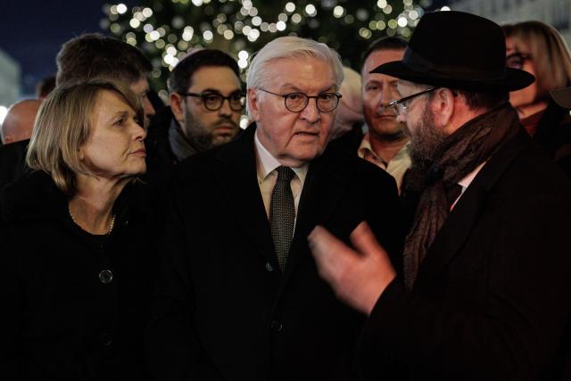 14 December 2025, Berlin: Rabbi Yehuda Teichtal (R) speaks with German President Frank-Walter Steinmeier (C) and Elke Büdenbender during the ceremony to light the first candle of the Hanukkah menorah on Pariser Platz in front of the Brandenburg Gate, marking the start of the Jewish festival of lights. Following the deadly attack on a Hanukkah celebration of the Chabad community at Bondi Beach in Sydney, they called for prayer. Photo: Carsten Koall/dpa