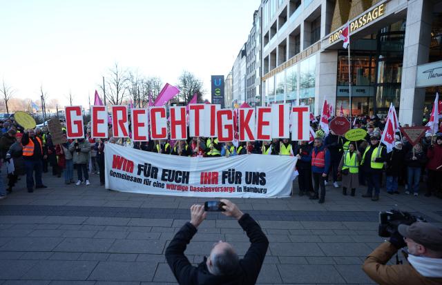 15 December 2025, Hamburg: People hold banners during the Public sector's warning strike in Hamburg. The trade union Verdi has called for a warning strike among public sector employees in the federal states. Photo: Marcus Brandt/dpa