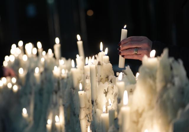 15 December 2025, Hamburg: A woman places a candle on the inverted candle tree in the main church of St. Petri during a press event on the Dorit and Alexander Otto Foundation's commitment to the preservation of Hamburg's main churches. Photo: Marcus Brandt/dpa
