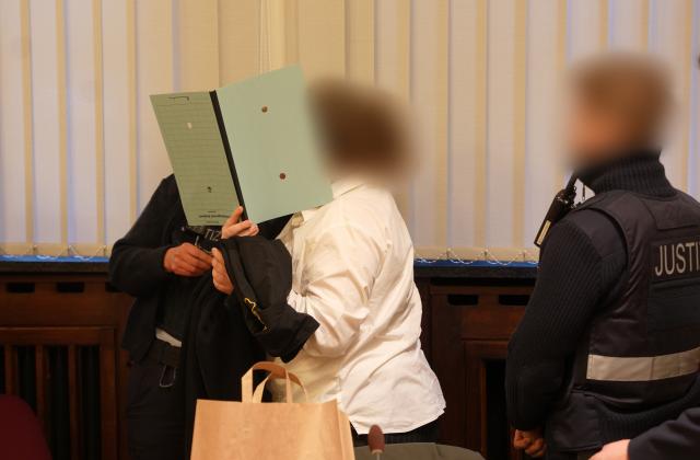 FILED - 11 January 2023, Rhineland-Palatinate, Koblenz: The 37-year-old defendant (M) is led into the courtroom of the Higher Regional Court. A German woman and member of the Islamic State terrorist organization who was convicted of abusing a Yezidi woman as a slave has had her sentence reduced by some nine months. Photo: Thomas Frey/dpa