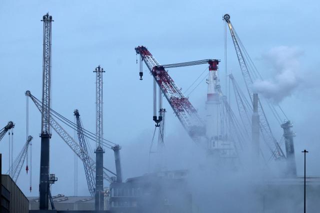 FILED - 09 December 2025, Mecklenburg-Western Pomerania, Rostock: In the overseas port on the Baltic Sea, steam rises in the morning from equipment at the grain terminal, with new mobile port cranes from the Liebherr-MCCtec Rostock crane factory in the background. Photo: Bernd Wüstneck/dpa