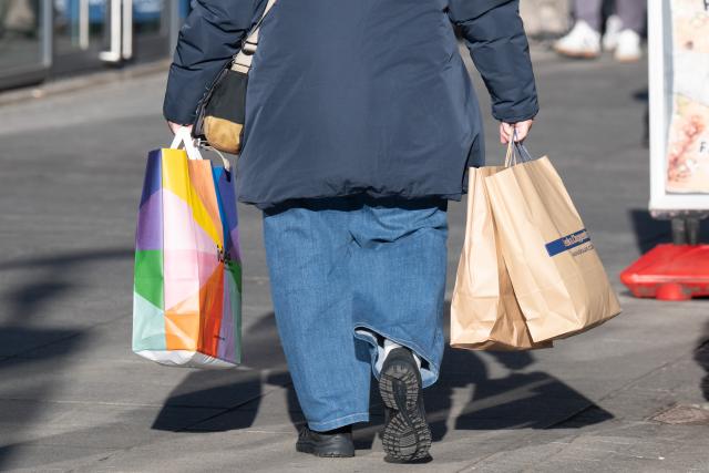 16 December 2025, Saxony, Dresden: A passer-by carries several shopping bags. Photo: Sebastian Kahnert/dpa