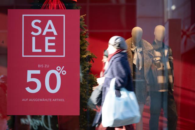 16 December 2025, Saxony, Dresden: A passer-by walks past a shop window labeled "Sale". Photo: Sebastian Kahnert/dpa