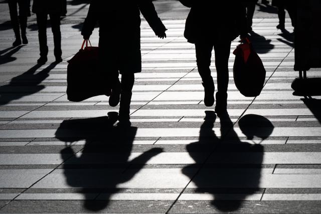 16 December 2025, Saxony, Dresden: Passers-by carrying shopping bags are silhouetted against the light. Photo: Sebastian Kahnert/dpa