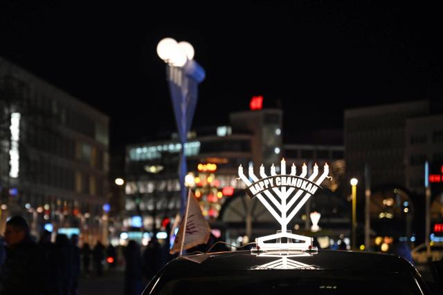 16 December 2025, Lower Saxony, Hanover: After a Hanukkah car parade, a vehicle with a Hanukkah menorah on its roof is parked at Opera Square. Several cars traveled from the House of Benjamin to the square for the celebration. Photo: Shireen Broszies/dpa