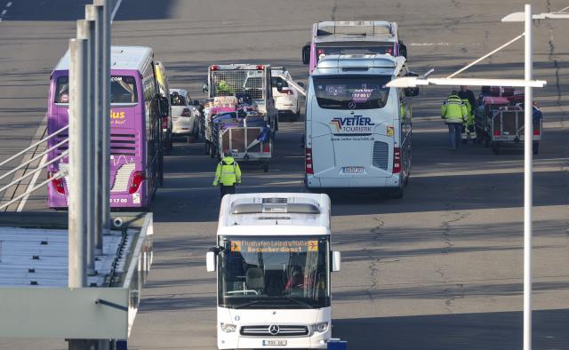 17 December 2025, Saxony, Schkeuditz: People load the luggage of migrants onto coaches at Leipzig/Halle Airport. The flight from Kenya took place as part of Germany's resettlement program. Photo: Jan Woitas/dpa