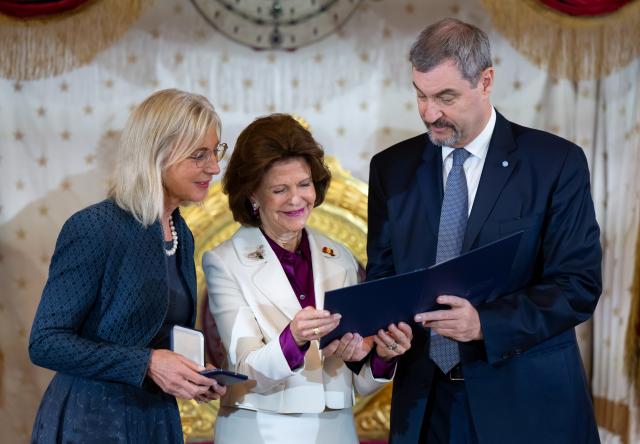 17 December 2025, Bavaria, Munich: Markus Soeder, Minister President of Bavaria, and Ulrike Scharf (L), Bavarian Minister of Social Affairs, award Queen Silvia of Sweden the Bavarian State Medal for her special social commitment. Photo: Sven Hoppe/dpa