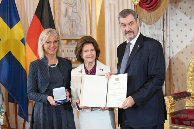 17 December 2025, Bavaria, Munich: Markus Soeder, Minister President of Bavaria, and Ulrike Scharf (L), Bavarian Minister of Social Affairs, award Queen Silvia of Sweden the Bavarian State Medal for her special social commitment at the Munich Residence. Photo: Felix Hörhager/dpa