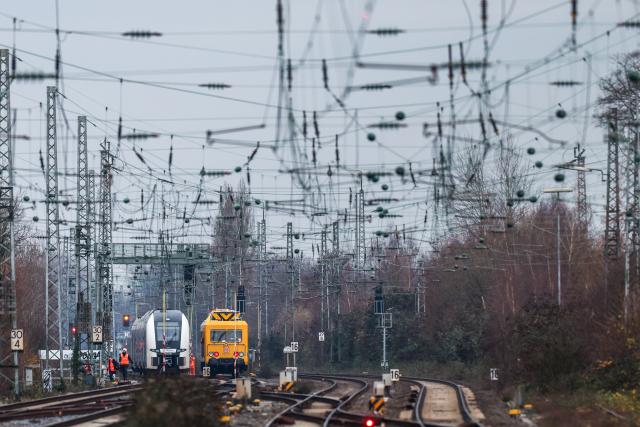 17 December 2025, North Rhine-Westphalia, Duesseldorf: A train is standing on the tracks on the open line, with a repair train on the right to repair the damage to the overhead line. Photo: Christoph Reichwein/dpa