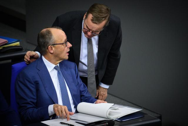 17 December 2025, Berlin: German Chancellor Friedrich Merz (L) and Boris Pistorius, German Minister of Defense, talk during the 49th plenary session of the 21st legislative period in the German Bundestag. Following a government inquiry and the Federal Chancellor's government statement on the EU summit to be held at the end of the week, the Bundestag discusses the Poverty and Wealth Report and the Bundeswehr mission in Iraq, among other things. Photo: Bernd von Jutrczenka/dpa