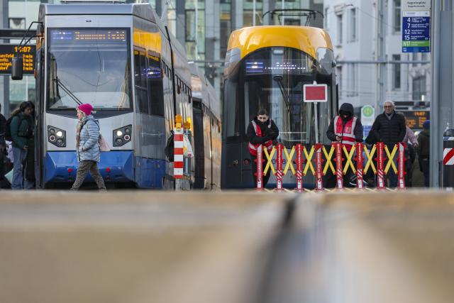 18 December 2025, Saxony, Leipzig: Two employees of a security company wait at a mobile barrier on the streetcar tracks at Augustusplatz. As part of the security measures for the Christmas market, these barriers always have to be opened and closed manually before the streetcars arrive and depart. Photo: Jan Woitas/dpa