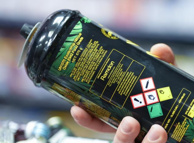 FILED - 13 November 2024, Hamburg: An employee holds a can of laughing gas at the counter of a kiosk. German lawmakers have passed a law banning people under 18 from possessing or purchasing nitrous oxide. Photo: Marcus Brandt/dpa
