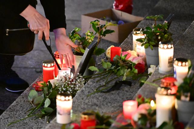 19 December 2025, Berlin: A woman lights a candle at the "Der Riss" memorial before the official commemoration of the 2016 attack on the Breitscheidplatz Christmas market. Photo: Sebastian Christoph Gollnow/dpa
