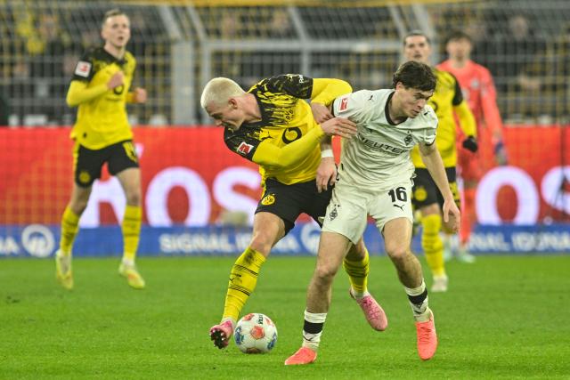 19 December 2025, North Rhine-Westphalia, Dortmund: Dortmund's Julian Ryerson and Gladbach's Philipp Sander in action during the German Bundesliga soccer match between Borussia Dortmund and Borussia Moenchengladbach at the Signal Iduna Park. Photo: Bernd Thissen/dpa
