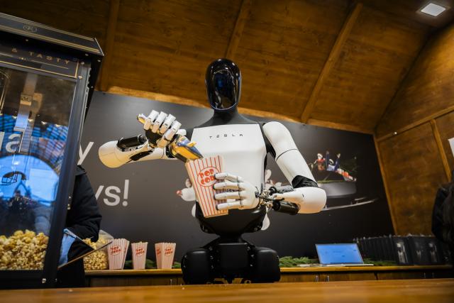 20 December 2025, Berlin: Tesla's humanoid robot 'Optimus' distributes popcorn at a Christmas market stall during its presentation at the Mall of Berlin. Photo: Christoph Soeder/dpa