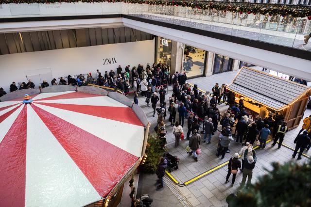 20 December 2025, Berlin: People queue to receive popcorn from Tesla's humanoid robot 'Optimus' at the Mall of Berlin. Photo: Christoph Soeder/dpa