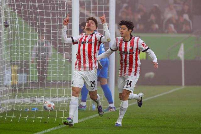 20 December 2025, Lower Saxony, Wolfsburg: Freiburg's Philipp Treu (L) celebrates after scoring his side's first goal of the game with Yuito Suzuki during the German Bundesliga soccer match between VfL Wolfsburg and SC Freiburg at Volkswagen Arena. Photo: Darius Simka/dpa - WICHTIGER HINWEIS: Gemäß den Vorgaben der DFL Deutsche Fußball Liga bzw. des DFB Deutscher Fußball-Bund ist es untersagt, in dem Stadion und/oder vom Spiel angefertigte Fotoaufnahmen in Form von Sequenzbildern und/oder videoähnlichen Fotostrecken zu verwerten bzw. verwerten zu lassen.