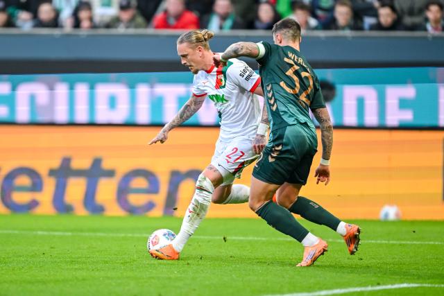 20 December 2025, Bavaria, Augsburg: Augsburg's Marius Wolf (L) and Werder Bremen's Marco Friedl battle for the ball during the German Bundesliga soccer match between FC Augsburg and Werder Bremen at WWK-Arena. Photo: Harry Langer/dpa - WICHTIGER HINWEIS: Gemäß den Vorgaben der DFL Deutsche Fußball Liga bzw. des DFB Deutscher Fußball-Bund ist es untersagt, in dem Stadion und/oder vom Spiel angefertigte Fotoaufnahmen in Form von Sequenzbildern und/oder videoähnlichen Fotostrecken zu verwerten bzw. verwerten zu lassen.