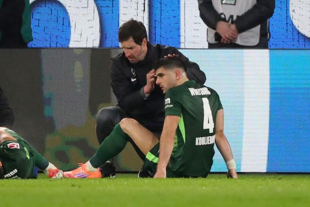 20 December 2025, Lower Saxony, Wolfsburg: Wolfsburg's Konstantinos Koulierakis is injured and has to be treated by team doctor Dr. Stephan Bornhardt during the German Bundesliga soccer match between VfL Wolfsburg and SC Freiburg at Volkswagen Arena. Photo: Darius Simka/dpa - WICHTIGER HINWEIS: Gemäß den Vorgaben der DFL Deutsche Fußball Liga bzw. des DFB Deutscher Fußball-Bund ist es untersagt, in dem Stadion und/oder vom Spiel angefertigte Fotoaufnahmen in Form von Sequenzbildern und/oder videoähnlichen Fotostrecken zu verwerten bzw. verwerten zu lassen.