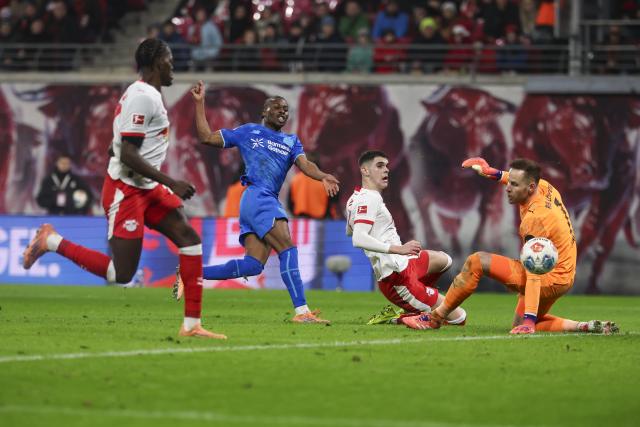 20 December 2025, Saxony, Leipzig: Bayer Leverkusen's Nathan Tella (C) fails to beat Leipzig's Kosta Nedeljkovie and Leipzig goalkeeper Peter Gulacsi during the German Bundesliga soccer match between RB Leipzig and Bayer Leverkusen at Red Bull Arena. Photo: Jan Woitas/dpa - WICHTIGER HINWEIS: Gemäß den Vorgaben der DFL Deutsche Fußball Liga bzw. des DFB Deutscher Fußball-Bund ist es untersagt, in dem Stadion und/oder vom Spiel angefertigte Fotoaufnahmen in Form von Sequenzbildern und/oder videoähnlichen Fotostrecken zu verwerten bzw. verwerten zu lassen.