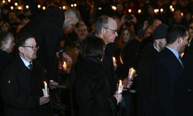 20 December 2025, Saxony-Anhalt, Magdeburg: Germany's Chancellor Friedrich Merz (C) joins his wife Charlotte in a chain of lights at a memorial service at St. John's Church in Magdeburg, one year after the attack on the Magdeburg Christmas market. On 20 December 2024, a man drove a car into a crowd, killing five women and a child and injuring more than 300 people. Photo: Hendrik Schmidt/dpa