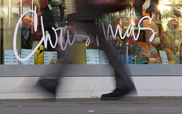 FILED - 17 December 2025, Hamburg: A passer-by walks past a department store with a festively decorated shop window and the inscription "Christmas". Photo: Marcus Brandt/dpa