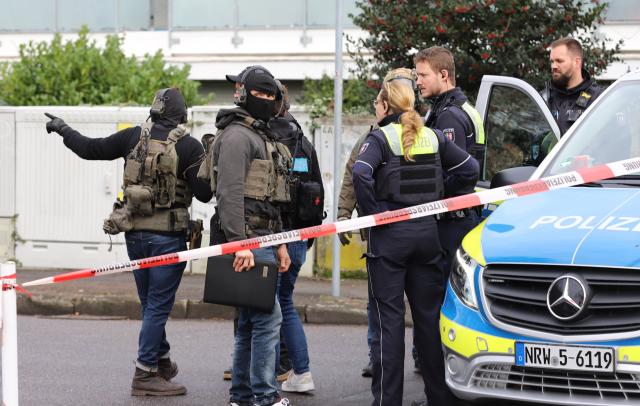 21 December 2025, North Rhine-Westphalia, Leverkusen: Special police forces talk to other police officers in front of a house during a police operation in Leverkusen. According to unconfirmed reports, there is an armed person in an apartment. Photo: Sascha Thelen/dpa