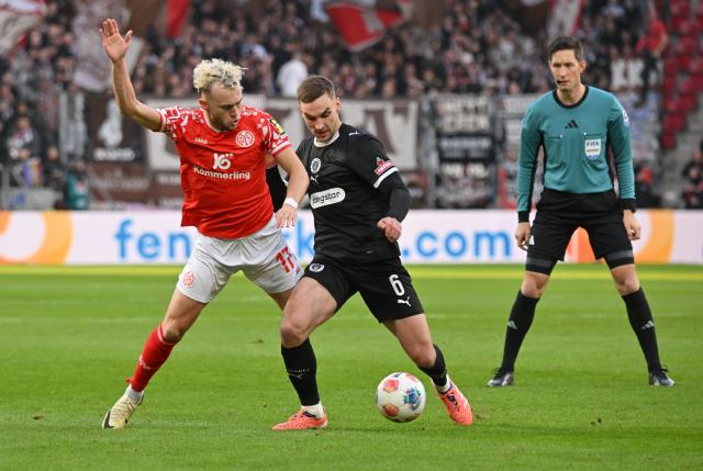 21 December 2025, Rhineland-Palatinate, Mainz: FSV Mainz's Benedict Hollerbach (L) and St. Pauli's James Sands battle for the ball during the German Bundesliga soccer match between FSV Mainz 05 and FC St. Pauli at Mewa Arena. Photo: Torsten Silz/dpa - WICHTIGER HINWEIS: Gemäß den Vorgaben der DFL Deutsche Fußball Liga bzw. des DFB Deutscher Fußball-Bund ist es untersagt, in dem Stadion und/oder vom Spiel angefertigte Fotoaufnahmen in Form von Sequenzbildern und/oder videoähnlichen Fotostrecken zu verwerten bzw. verwerten zu lassen.
