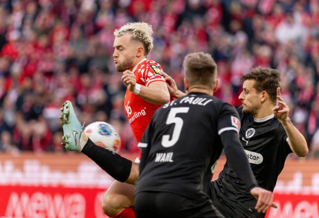 21 December 2025, Rhineland-Palatinate, Mainz: FSV Mainz's Benedict Hollerbach (L) and St. Pauli's Adam Dzwigala (R) battle for the ball during the German Bundesliga soccer match between FSV Mainz 05 and FC St. Pauli at Mewa Arena. Photo: Torsten Silz/dpa - WICHTIGER HINWEIS: Gemäß den Vorgaben der DFL Deutsche Fußball Liga bzw. des DFB Deutscher Fußball-Bund ist es untersagt, in dem Stadion und/oder vom Spiel angefertigte Fotoaufnahmen in Form von Sequenzbildern und/oder videoähnlichen Fotostrecken zu verwerten bzw. verwerten zu lassen.