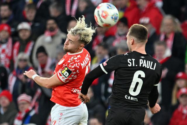 21 December 2025, Rhineland-Palatinate, Mainz: Mainz's Benedict Hollerbach (L) and St. Pauli's James Sands battle for the ball during the German Bundesliga soccer match between FSV Mainz 05 and FC St. Pauli at Mewa Arena. Photo: Torsten Silz/dpa - WICHTIGER HINWEIS: Gemäß den Vorgaben der DFL Deutsche Fußball Liga bzw. des DFB Deutscher Fußball-Bund ist es untersagt, in dem Stadion und/oder vom Spiel angefertigte Fotoaufnahmen in Form von Sequenzbildern und/oder videoähnlichen Fotostrecken zu verwerten bzw. verwerten zu lassen.