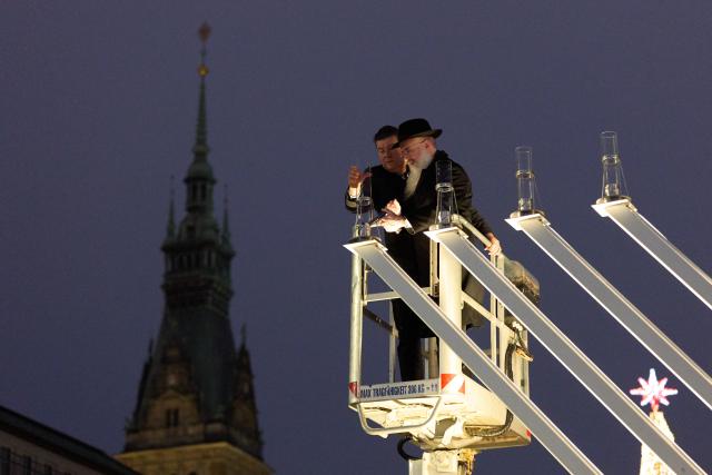 21 December 2025, Hamburg: Hamburg Senator for Finance Andreas Dressel (L) and Rabbi of the Free and Hanseatic City of Hamburg Shlomo Bistritzky light the Hanukkah candelabra on the Reesendamm bridge at Jungfernstieg. Photo: Georg Wendt/dpa
