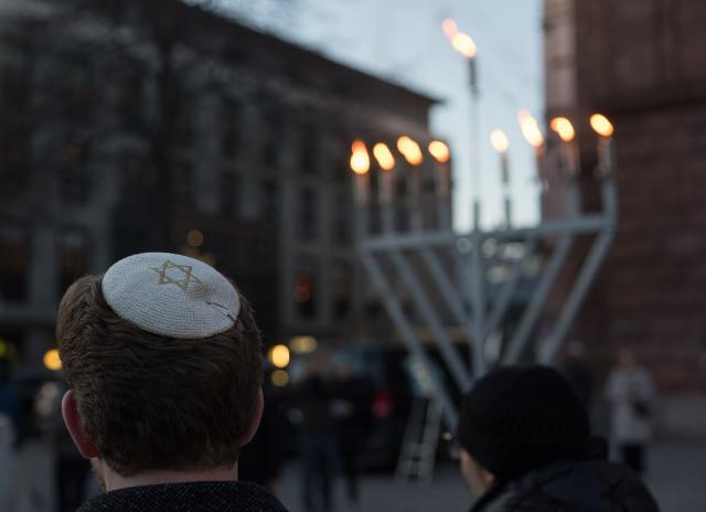 21 December 2025, Rhineland-Palatinate, Mainz: A participant with a kippah stands in front of a Hanukkia during the annual joint candle-lighting ceremony for Hanukkah orgnized by The state association of Jewish communities in Rhineland-Palatinate. Photo: Hannes P. Albert/dpa