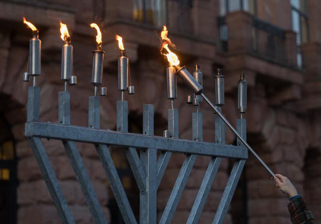21 December 2025, Rhineland-Palatinate, Mainz: A candle is lit on a Hanukkia at the annual joint candle-lighting ceremony for Hanukkah orgnized by The state association of Jewish communities in Rhineland-Palatinate. Photo: Hannes P. Albert/dpa