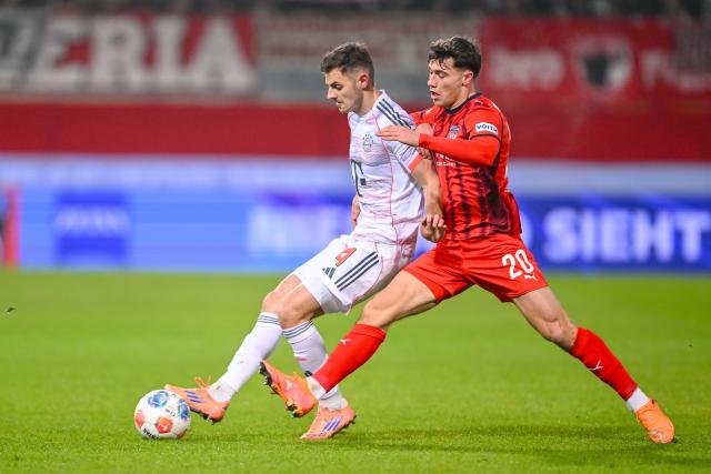 21 December 2025, Baden-Wuerttemberg, Heidenheim: Bayern Munich's Josip Stanisic (L) and Heidenheim's Luca Kerber battle for the ball during the German Bundesliga soccer match between 1. FC Heidenheim and Bayern Munich at Voith-Arena. Photo: Harry Langer/dpa - WICHTIGER HINWEIS: Gemäß den Vorgaben der DFL Deutsche Fußball Liga bzw. des DFB Deutscher Fußball-Bund ist es untersagt, in dem Stadion und/oder vom Spiel angefertigte Fotoaufnahmen in Form von Sequenzbildern und/oder videoähnlichen Fotostrecken zu verwerten bzw. verwerten zu lassen.