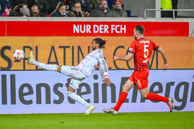 21 December 2025, Baden-Wuerttemberg, Heidenheim: Bayern Munich's Michael Olise (L) and Heidenheim's Benedikt Gimber battle for the ball during the German Bundesliga soccer match between 1. FC Heidenheim and Bayern Munich at Voith-Arena. Photo: Harry Langer/dpa - WICHTIGER HINWEIS: Gemäß den Vorgaben der DFL Deutsche Fußball Liga bzw. des DFB Deutscher Fußball-Bund ist es untersagt, in dem Stadion und/oder vom Spiel angefertigte Fotoaufnahmen in Form von Sequenzbildern und/oder videoähnlichen Fotostrecken zu verwerten bzw. verwerten zu lassen.