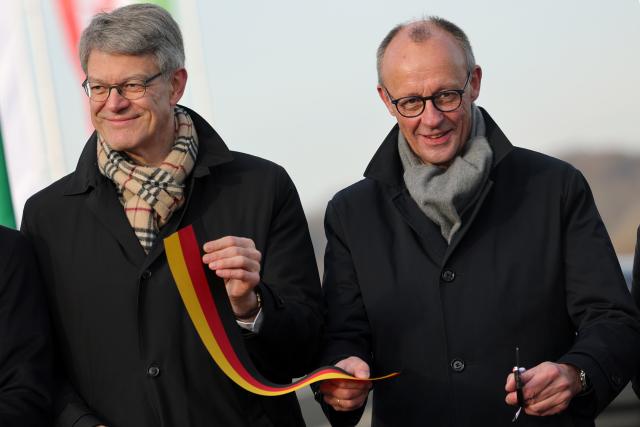 22 December 2025, North Rhine-Westphalia, Lüdenscheid: German Transport Minister Patrick Schnieder (L) and German Chancellor Friedrich Merz cut a ribbon at the opening of the Rahmedetal bridge. The important A45 north-south axis in the Sauerland region was interrupted for almost four years due to a dilapidated bridge. The dilapidated bridge was closed at the beginning of December 2021 and later blown up. Photo: Rolf Vennenbernd/dpa