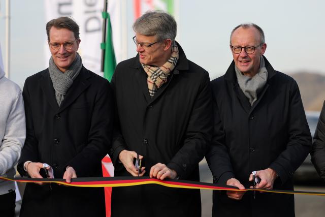 22 December 2025, North Rhine-Westphalia, Lüdenscheid: Hendrik Wuest (l-r), Minister President of North Rhine-Westphalia, Federal Transport Minister Patrick Schnieder and German Chancellor Friedrich Merz cut a ribbon at the opening of the Rahmedetal Bridge. The important A45 north-south axis in the Sauerland region was interrupted for almost four years due to a dilapidated bridge. The dilapidated bridge was closed at the beginning of December 2021 and later blown up. Photo: Rolf Vennenbernd/dpa