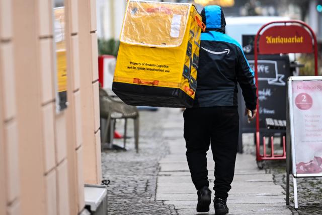PRODUCTION - 22 December 2025, Berlin: An employee of the online mail order company Amazon delivers parcels in the old town of Köpenick shortly before Christmas. Photo: Britta Pedersen/dpa