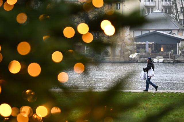 PRODUCTION - 22 December 2025, Berlin: A young man carrying shopping bags walks along the banks of the Mueggelspree in the old town of Koepenick. Photo: Britta Pedersen/dpa