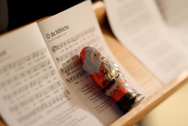 24 December 2025, Thuringia, Rohnstedt: A chocolate Santa Claus lies on a hymn book during the Christmas Eve service. Photo: Matthias Bein/dpa