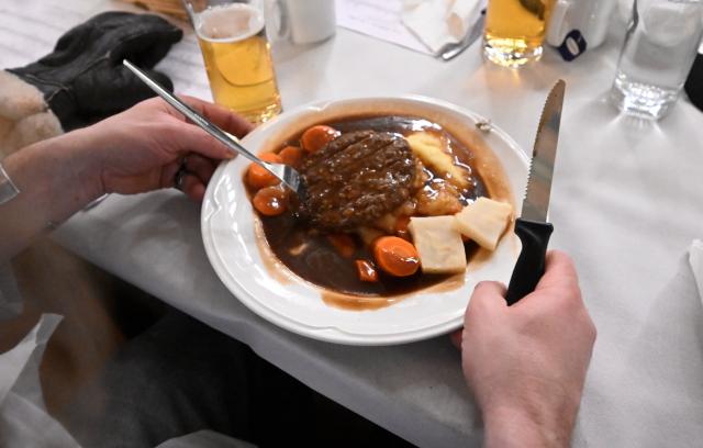 24 December 2025, Bavaria, Munich: A victim holds a plate in his hands at the Christmas party of the Catholic Men's Welfare Association for Homeless People in the ballroom of the Hofbraeuhaus in Munich. Photo: Felix Hörhager/dpa