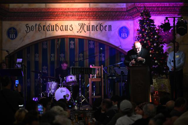 24 December 2025, Bavaria, Munich: Cardinal Reinhard Marx (R) speaks at the Christmas party of the Catholic Men's Welfare Association for homeless people in the ballroom of the Hofbraeuhaus in Munich. Photo: Felix Hörhager/dpa