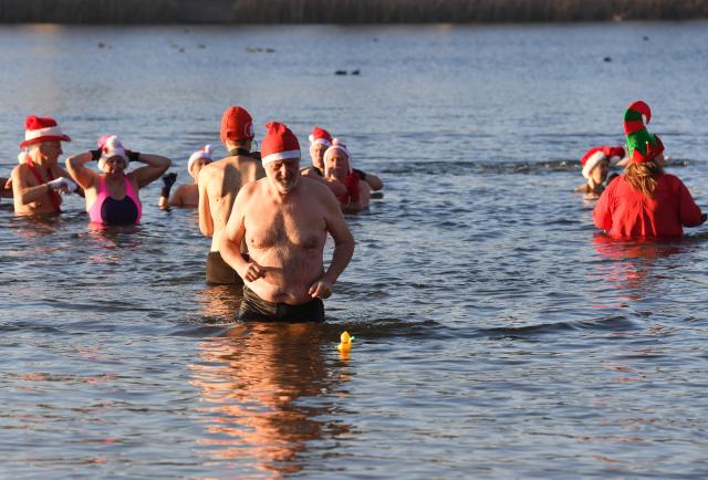 25 December 2025, Berlin: Numerous water enthusiasts brave sub-zero temperatures during the Christmas swim organized by the Berlin Seal Club at Orankesee. With the water at just under one degree Celsius, participants are only able to remain in the lake for a short time. Photo: Paul Zinken/dpa