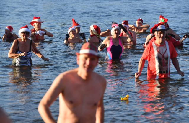 25 December 2025, Berlin: Numerous water enthusiasts brave sub-zero temperatures during the Christmas swim organized by the Berlin Seal Club at Orankesee. With the water at just under one degree Celsius, participants are only able to remain in the lake for a short time. Photo: Paul Zinken/dpa