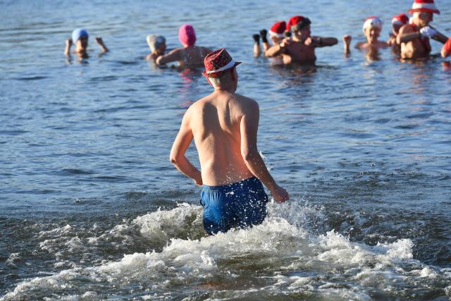 25 December 2025, Berlin: Numerous water enthusiasts brave sub-zero temperatures during the Christmas swim organized by the Berlin Seal Club at Orankesee. With the water at just under one degree Celsius, participants are only able to remain in the lake for a short time. Photo: Paul Zinken/dpa