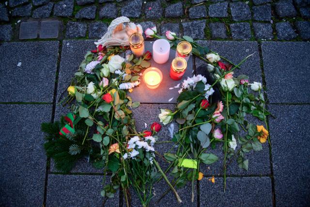 FILED - 20 December 2025, Saxony-Anhalt, Magdeburg: Candles and flowers surround a memorial plaque in the sidewalk in commemoration of victim of the attack on Magdeburg's Christmas market. A year ago, a man drove a rental car through the market - six people died and more than 300 were injured; today, the Christmas market remains closed to mark the occasion. Photo: Klaus-Dietmar Gabbert/dpa